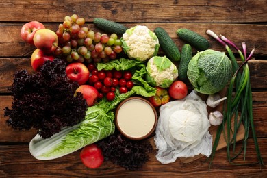 Photo of Different fresh ripe vegetables, sour cream, cottage cheese and fruits on wooden table, flat lay. Farmer produce
