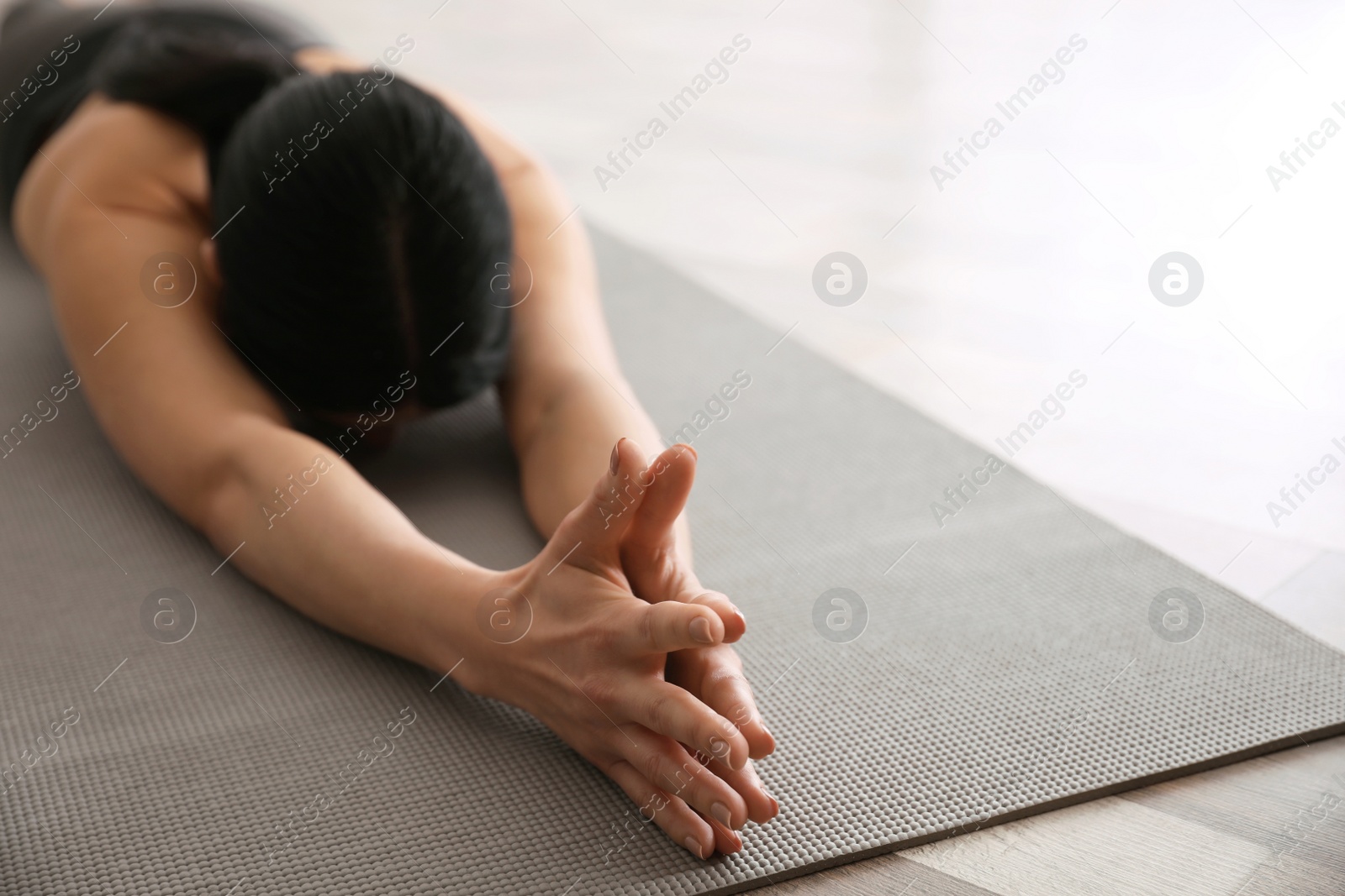 Photo of Young woman practicing extended child's asana in yoga studio, closeup. Utthita Balasana pose