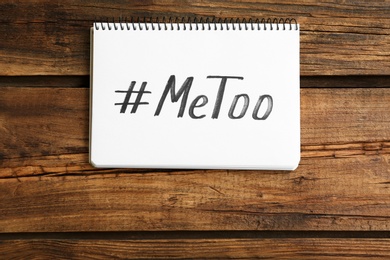 Photo of Notebook with hashtag METOO on wooden background, top view. Stop sexual assault