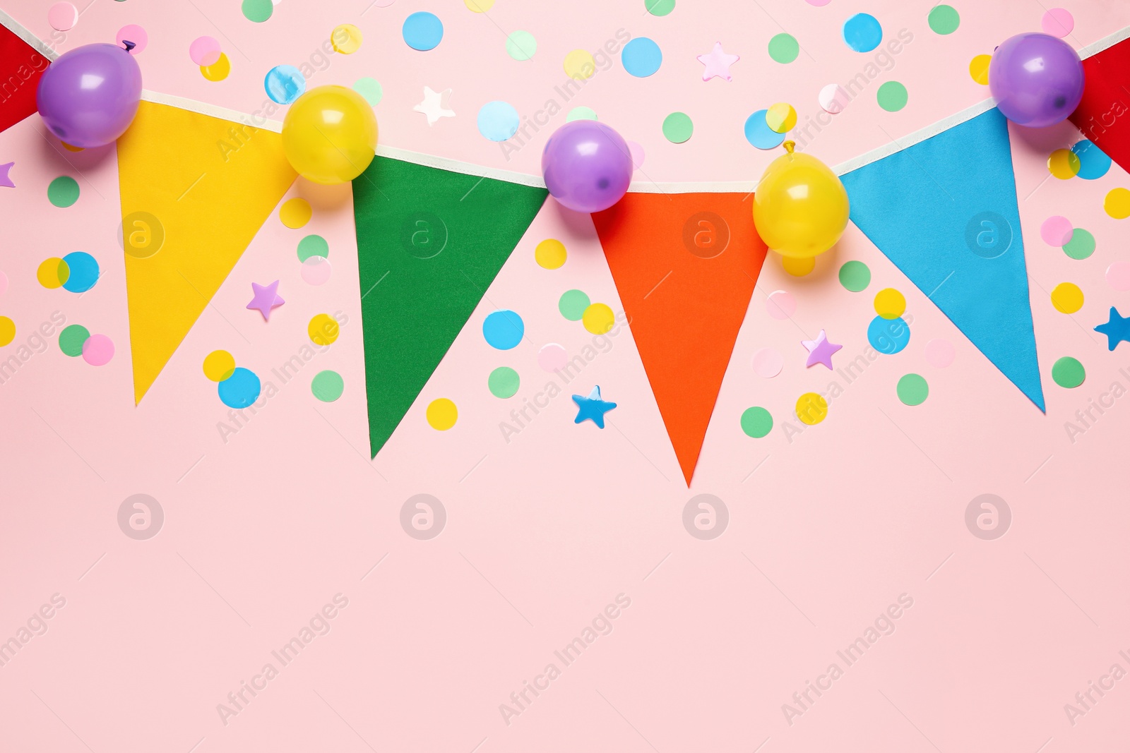 Photo of Bunting with colorful triangular flags and other festive decor on pink background, flat lay. Space for text