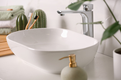 Photo of Stylish vessel sink on light countertop in modern bathroom, closeup