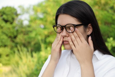 Young woman suffering from eyestrain outdoors on sunny day
