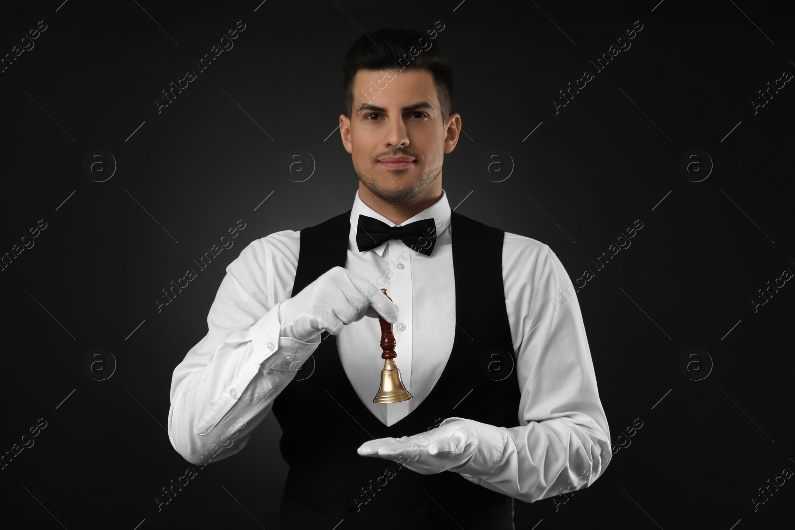 Photo of Butler holding hand bell on black background, space for text