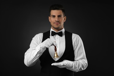 Photo of Butler holding hand bell on black background, space for text