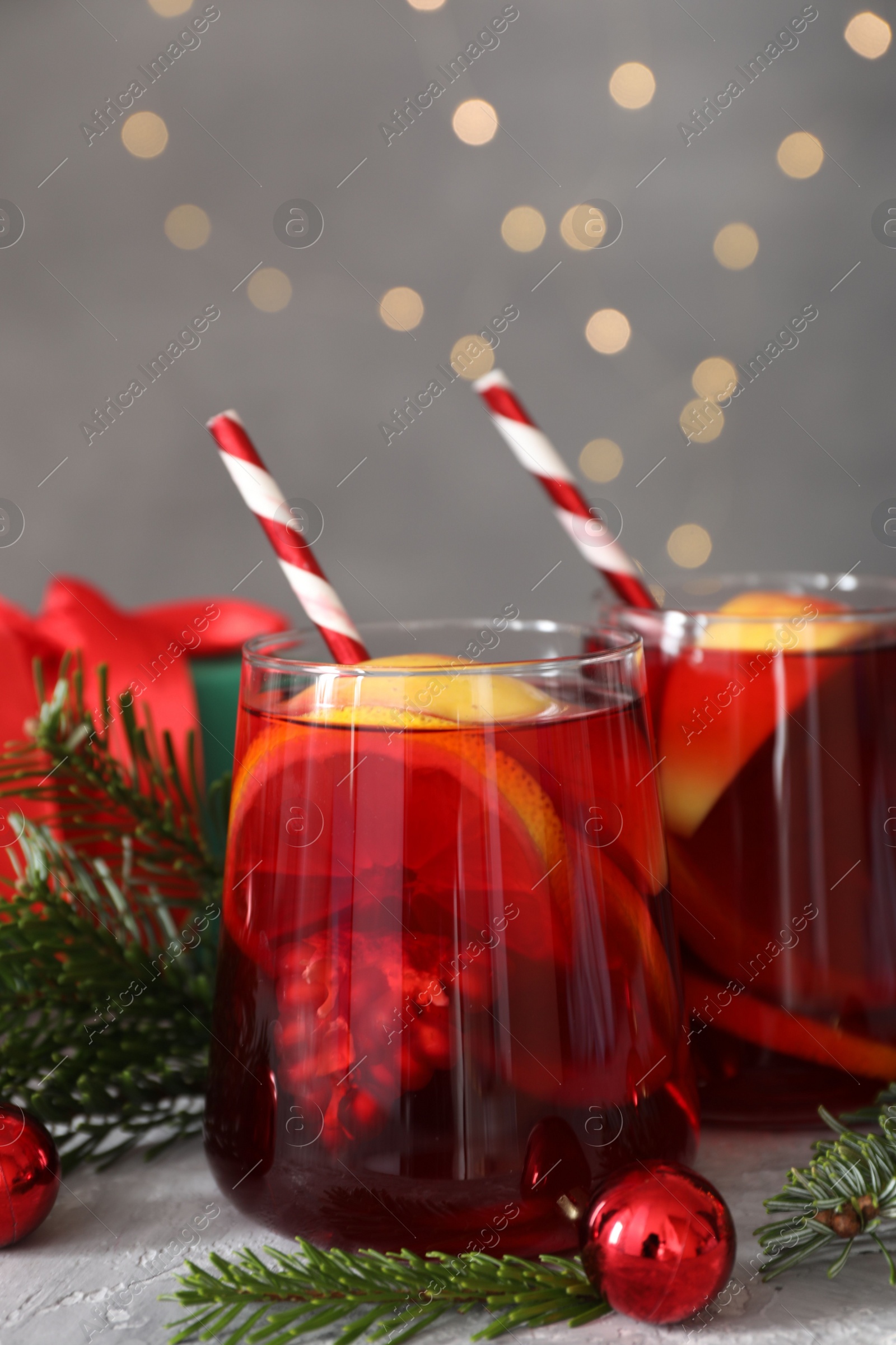 Photo of Delicious Sangria drink in glasses and Christmas decorations on grey table, closeup