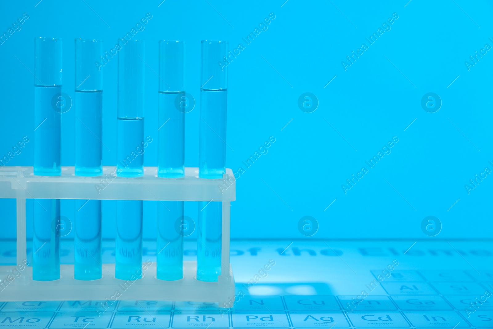 Photo of Test tubes on periodic table of elements, toned in light blue. Space for text