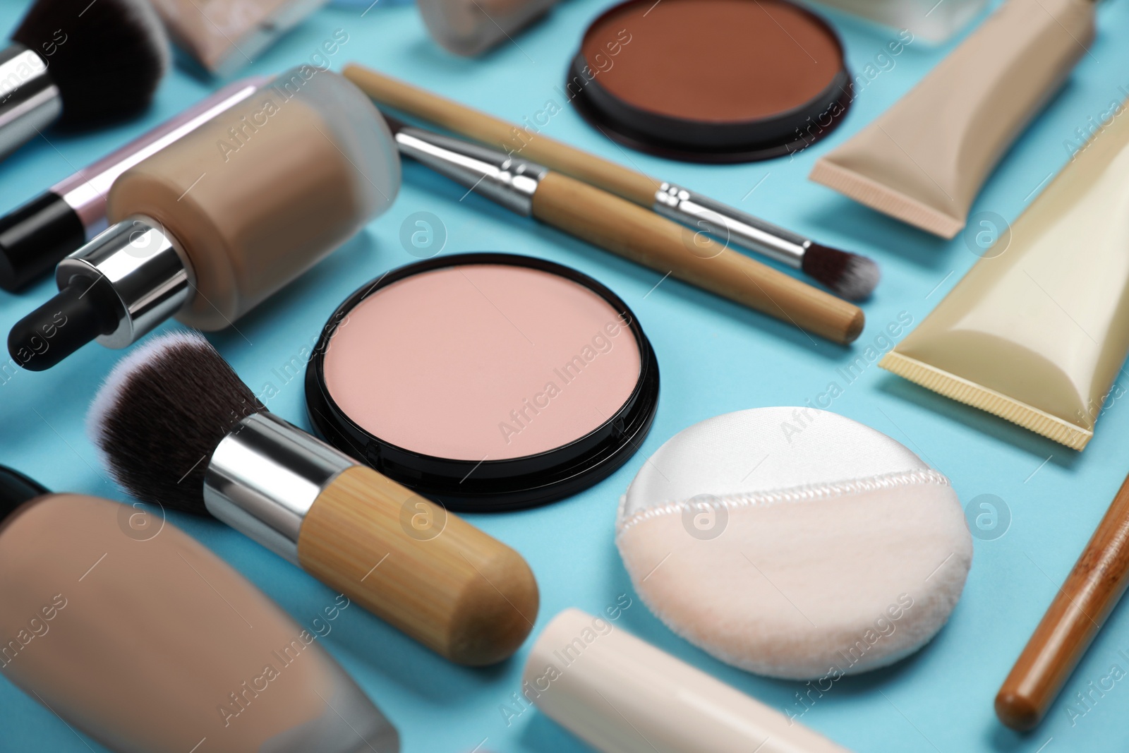 Photo of Face powders and other decorative cosmetic products on light blue background