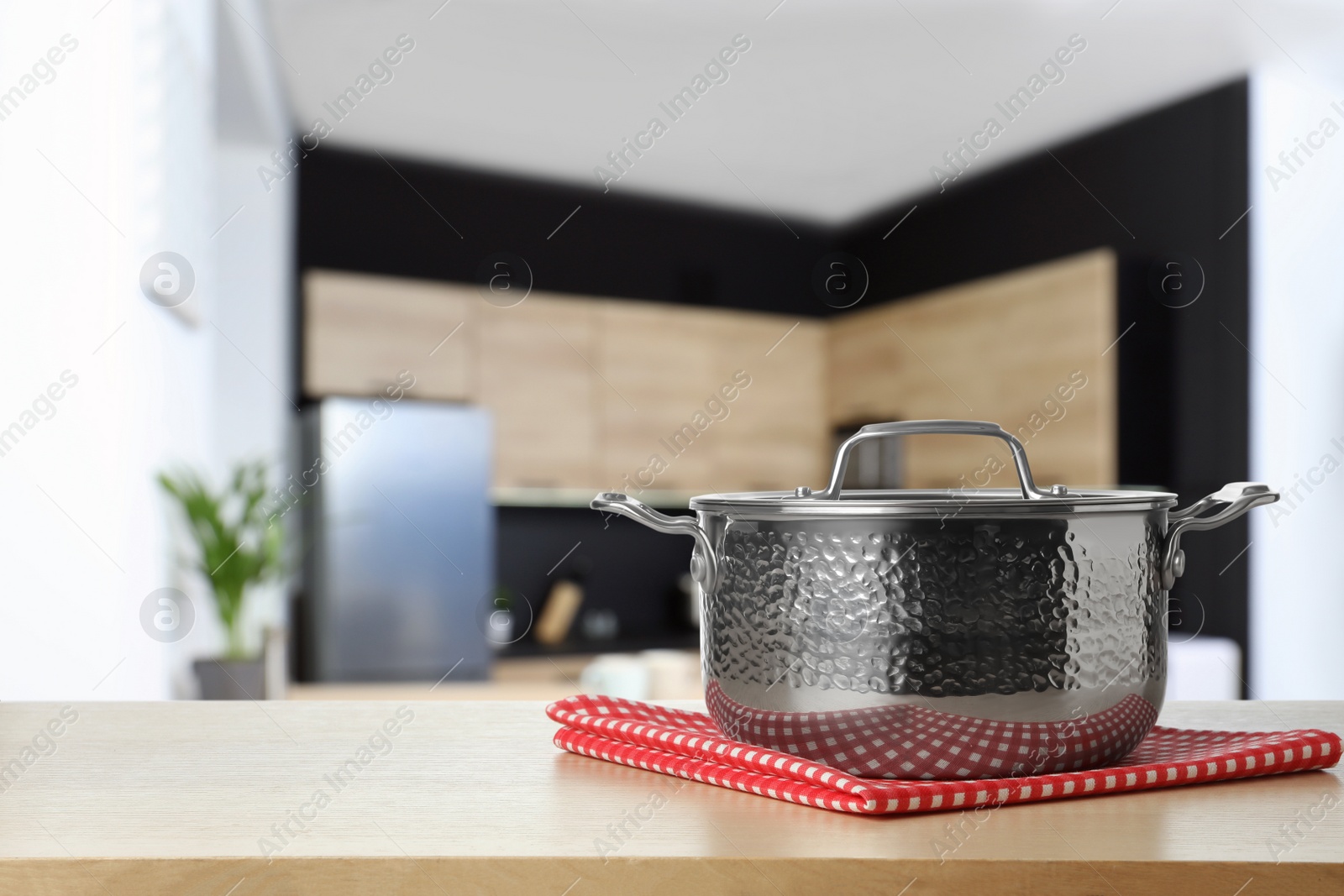 Image of Towel and pot on wooden table in kitchen. Space for text