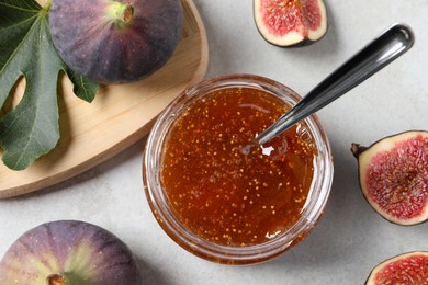 Jar with tasty sweet jam and fresh figs on white table, flat lay