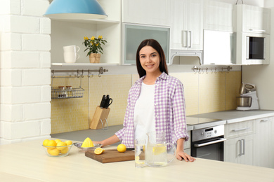 Photo of Beautiful young woman making lemon water in kitchen