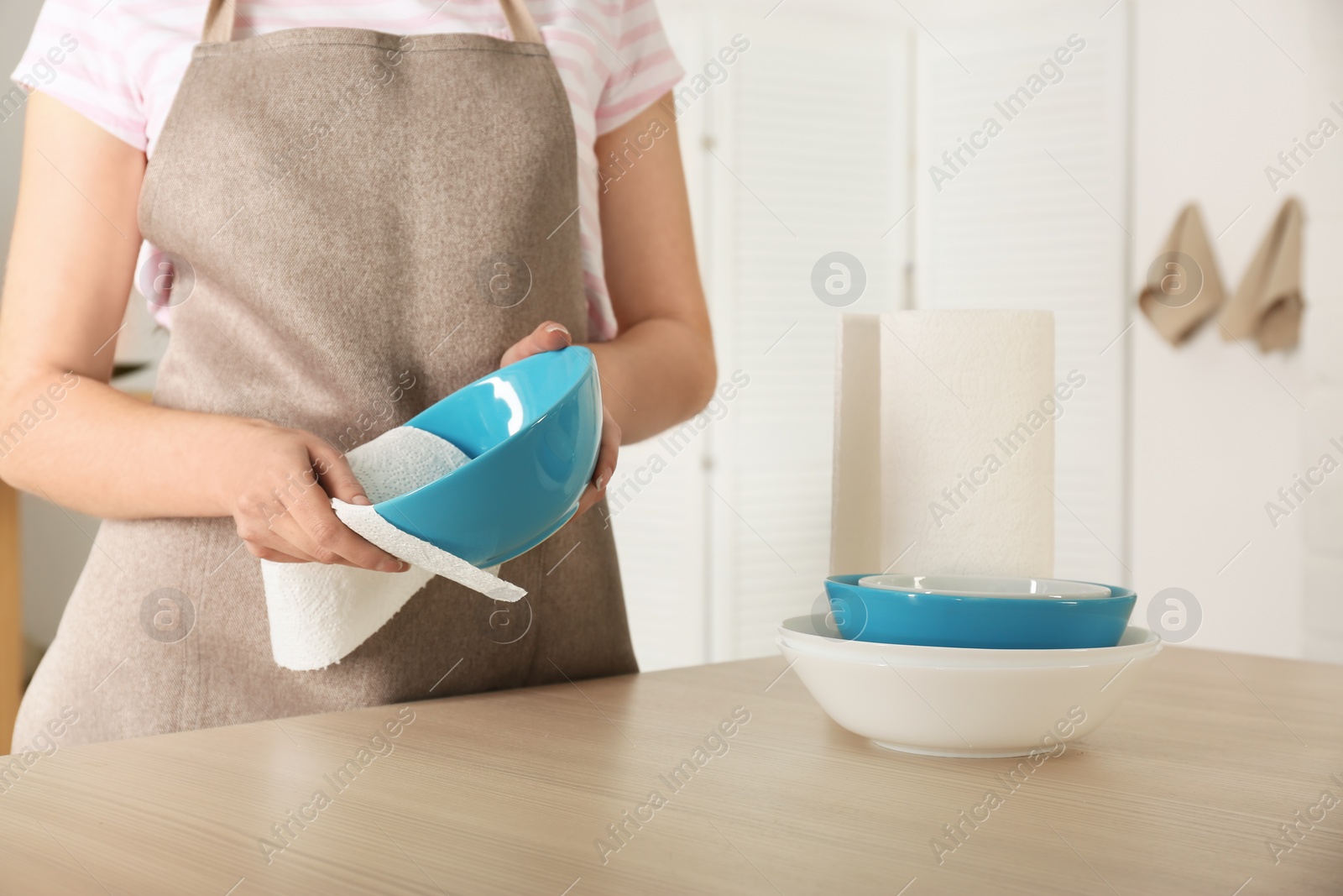 Photo of Woman wiping bowl with paper towel in kitchen, closeup