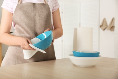 Woman wiping bowl with paper towel in kitchen, closeup