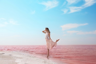 Photo of Beautiful woman posing near pink lake on sunny day