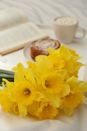 Bouquet of beautiful daffodils on white bed, closeup