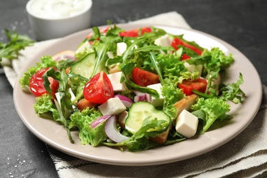 Photo of Delicious salad with meat, arugula and vegetables on black table, closeup