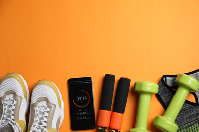 Photo of Flat lay composition with fitness equipment and smartphone on orange background, space for text