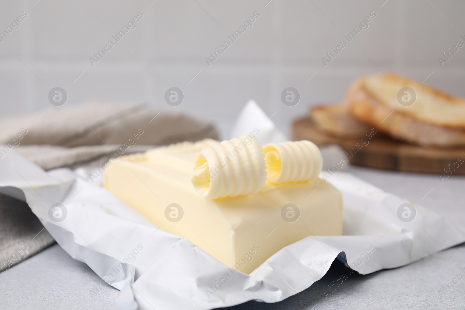 Photo of Tasty butter and curls on light grey table, closeup