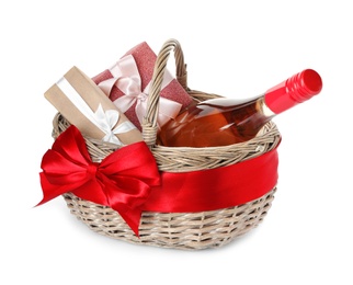 Photo of Festive basket with bottle of wine and gifts on white background