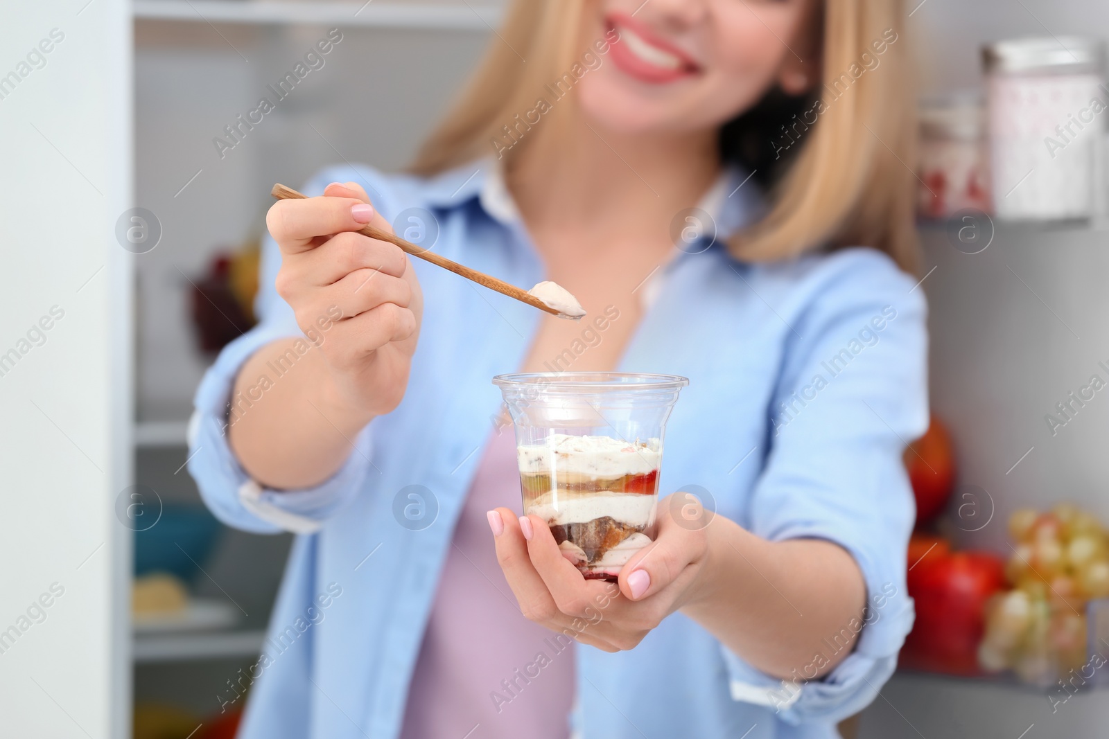 Photo of Young woman with yogurt in kitchen, closeup