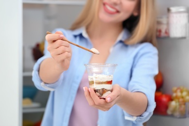 Photo of Young woman with yogurt in kitchen, closeup