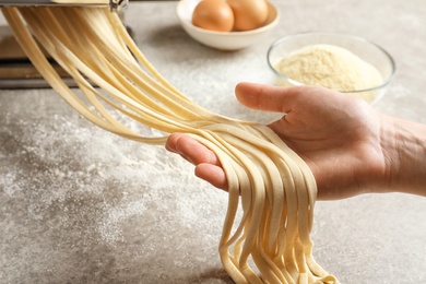 Young woman preparing pasta at table, closeup