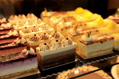 Photo of Different delicious cakes on counter in bakery shop, closeup