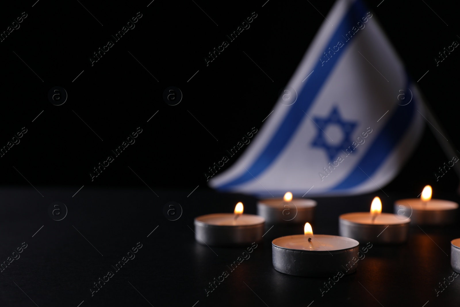 Photo of Burning candles on black table, space for text. Holocaust memory day