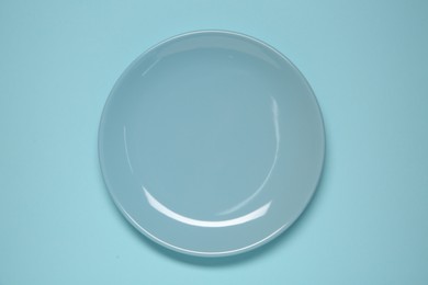 Photo of One ceramic plate on light blue background, top view