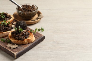 Photo of Delicious bruschettas with truffle sauce and microgreens on white wooden table. Space for text