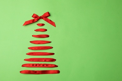 Photo of Christmas tree made of ribbons on green background, top view. Space for text