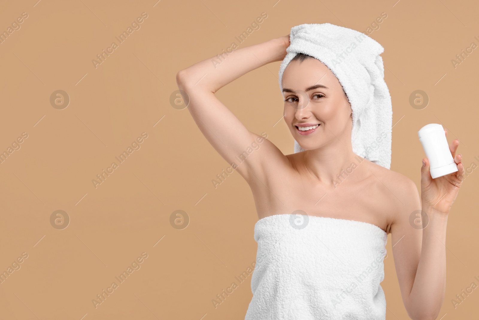 Photo of Beautiful woman applying deodorant on beige background, space for text
