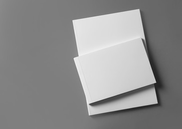 Photo of Brochures with blank covers on light grey background, top view. Space for text