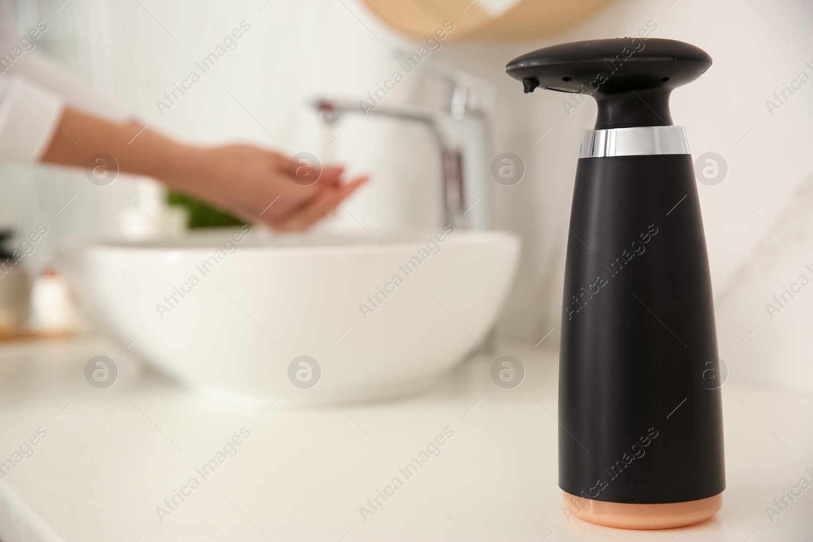 Photo of Modern automatic soap dispenser on countertop in bathroom