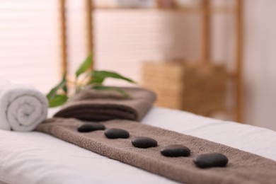 Towel with arranged spa stones on massage table in recreational center