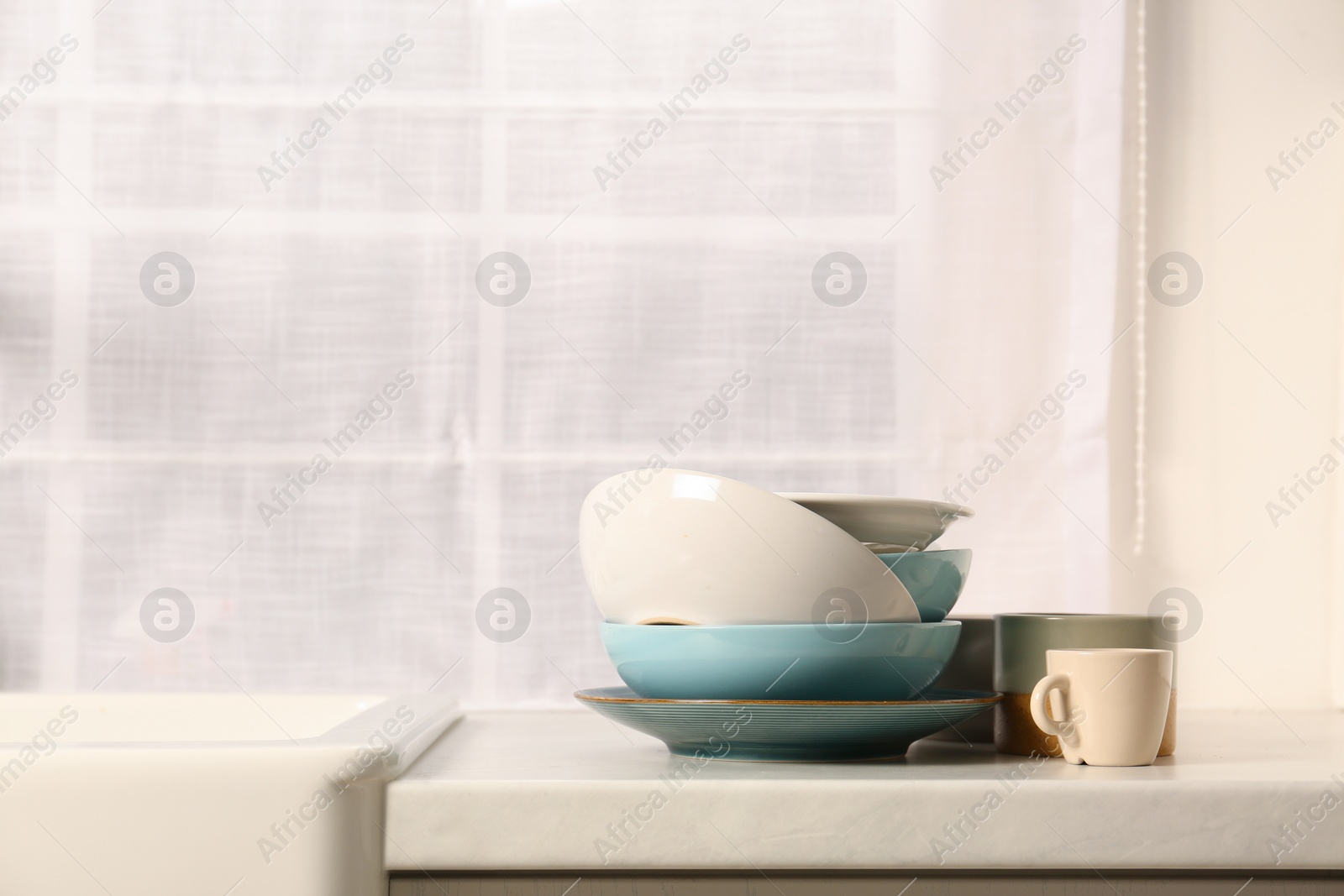 Photo of Clean tableware on light countertop in kitchen, space for text