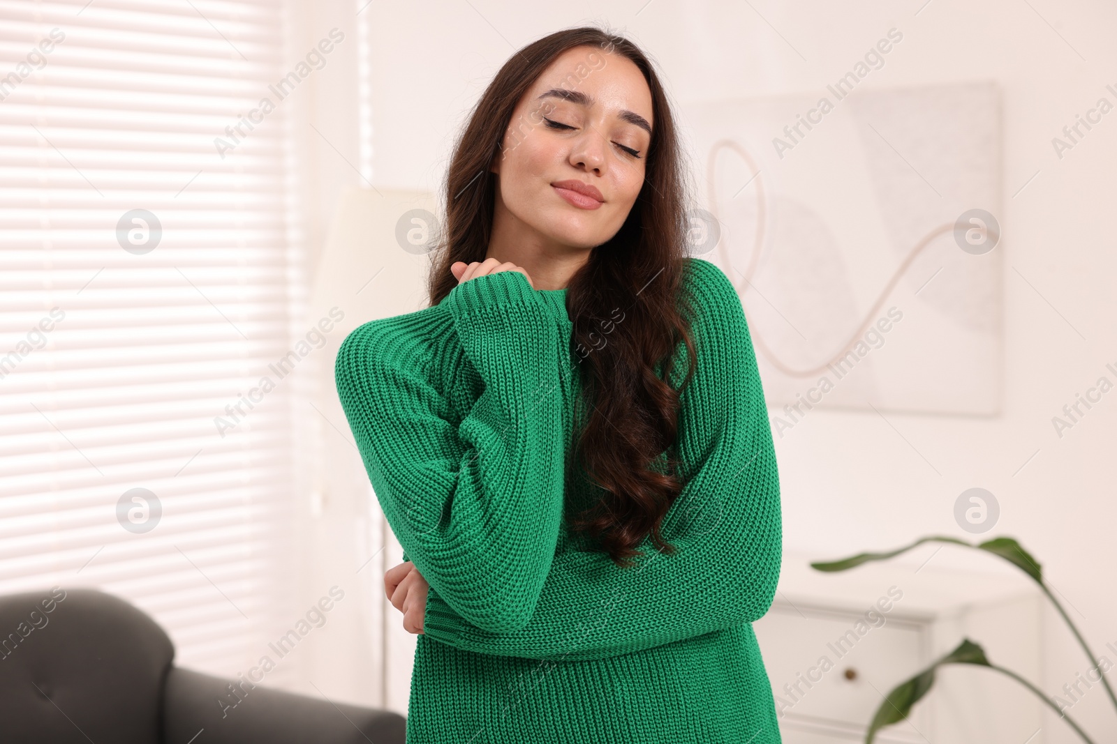 Photo of Beautiful young woman in stylish warm sweater at home