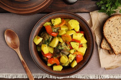 Tasty cooked dish with potatoes in earthenware on table, flat lay