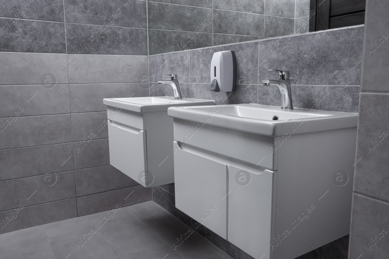 Photo of Public toilet interior with stylish white sinks and grey tiles