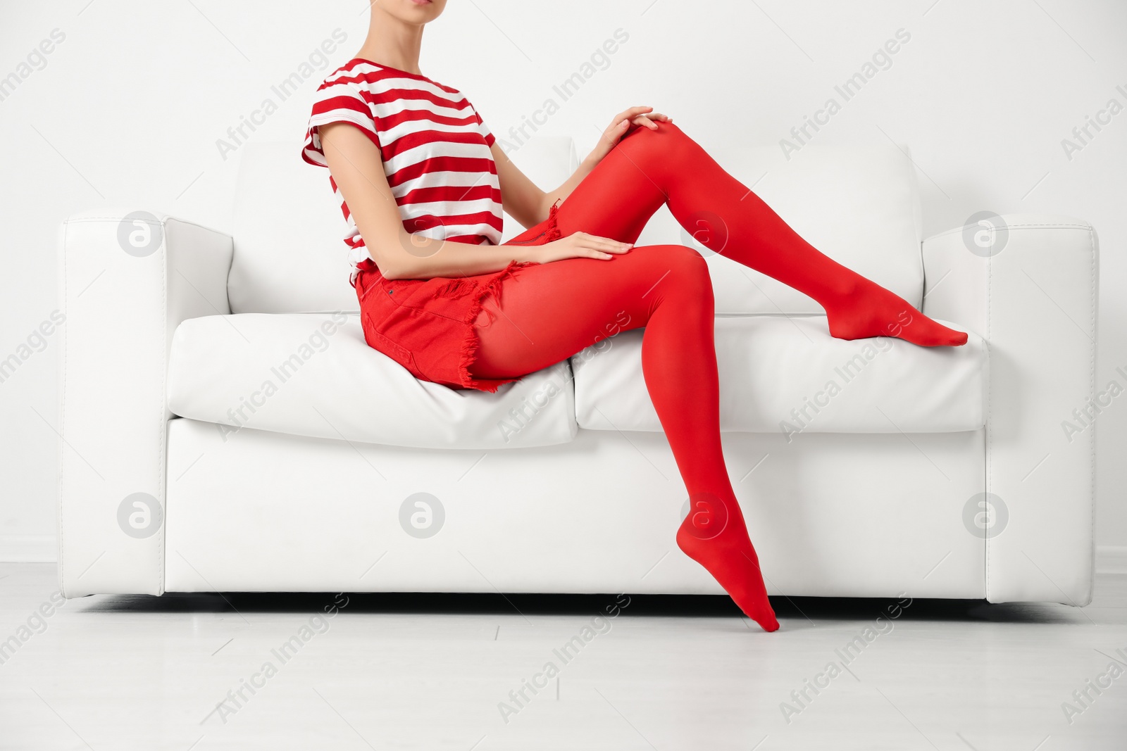 Photo of Woman wearing red tights sitting on sofa indoors, closeup