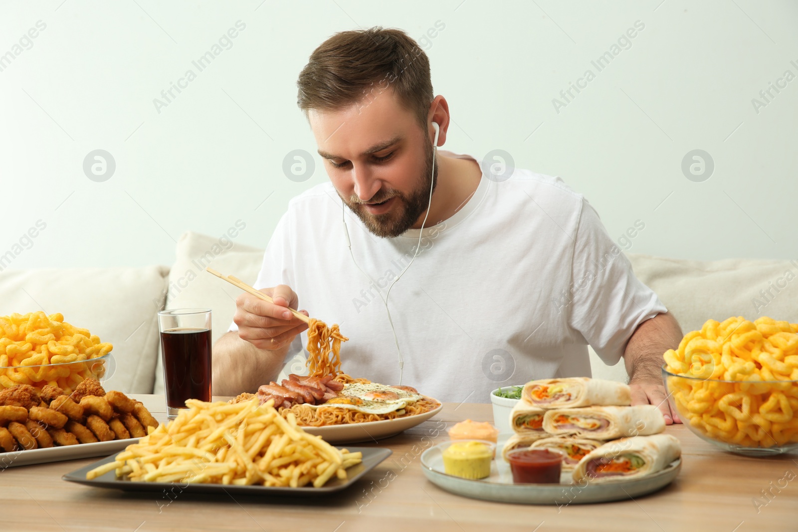 Photo of Food blogger eating at table against light background. Mukbang vlog