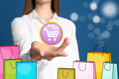 Image of Online shopping. Woman demonstrating cart illustration against blue background with paper bags, closeup