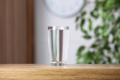 Photo of Glass of pure water on wooden table indoors