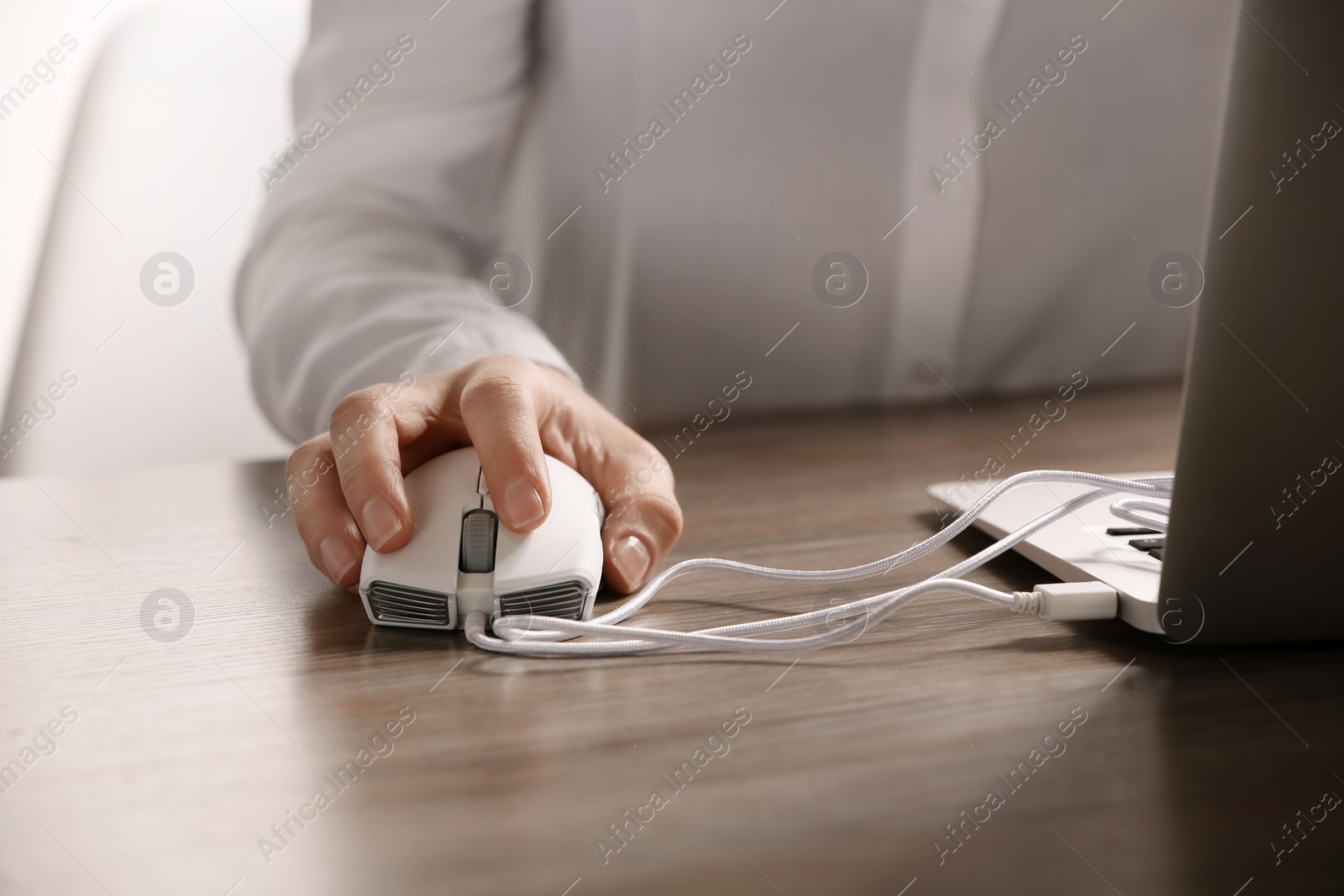 Photo of Woman using computer mouse with laptop at table, closeup