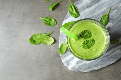 Flat lay composition with fresh green healthy spinach smoothie on grey table. Space for text