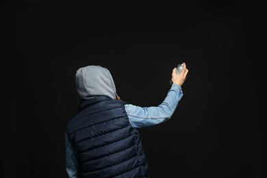 Man holding used can of spray paint on black background, back view