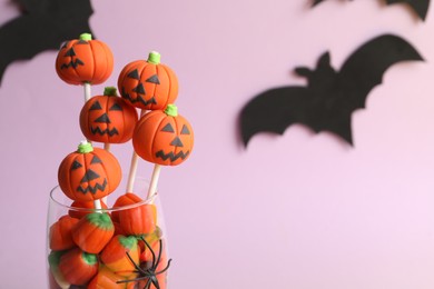 Photo of Delicious Halloween themed cake pops on pink background, closeup. Space for text