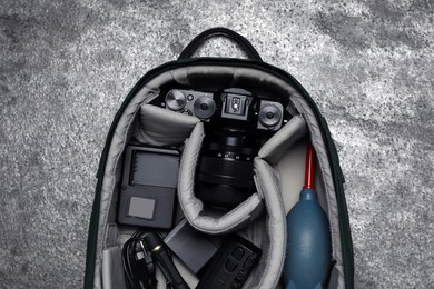 Professional photography equipment in backpack on grey stone table, top view