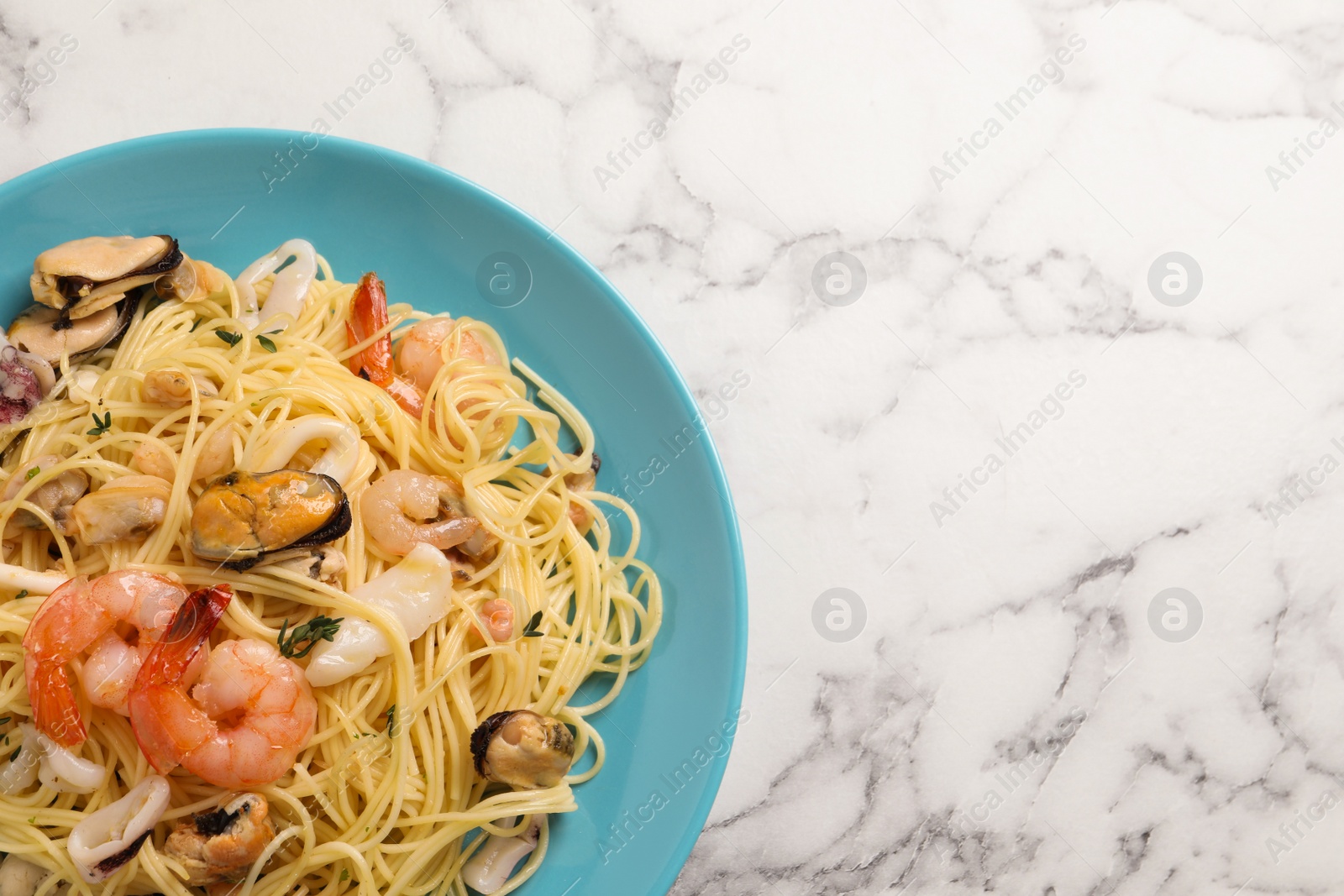 Photo of Delicious pasta with sea food on white marble table, top view. Space for text