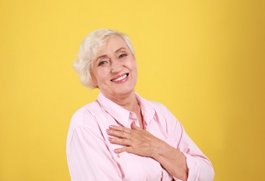 Emotional senior woman in casual outfit on yellow background