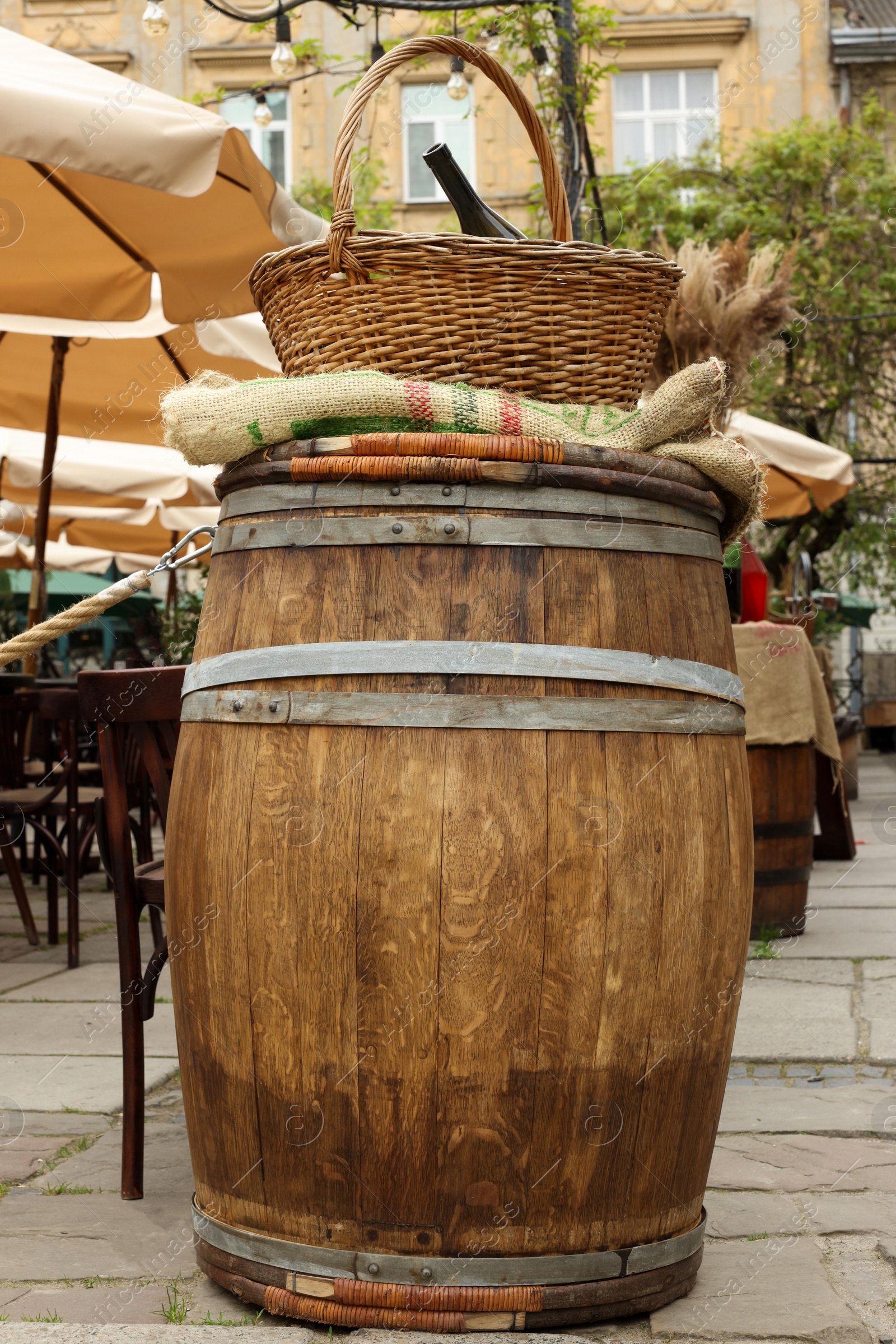 Photo of Traditional wooden barrel and basket with wine bottle in outdoor cafe